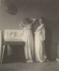 Twee vrouwelijke modellen in klassieke kostuums met Eakins-sculptuur Arcadia